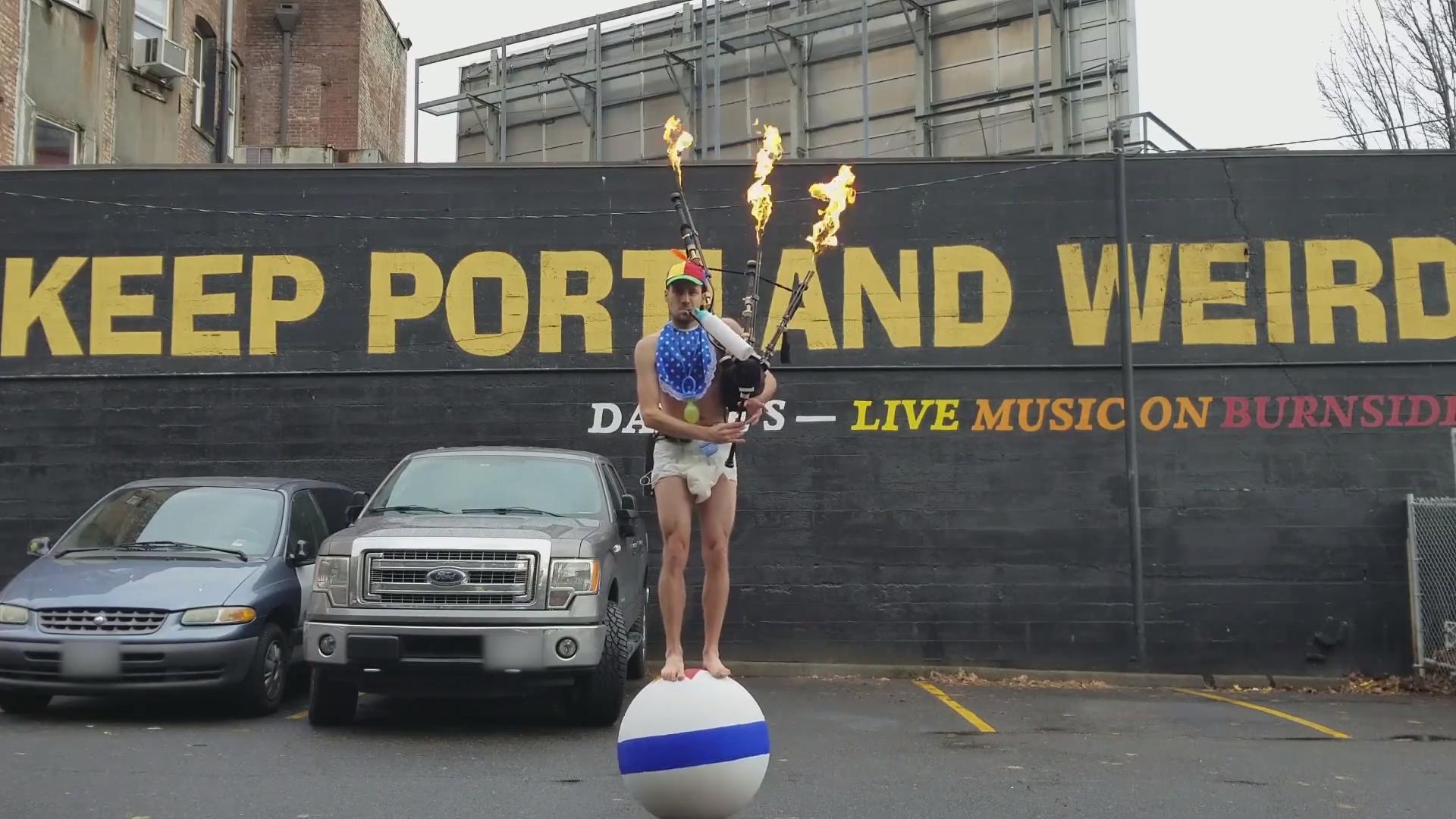 Guy Riding Unicycle and Playing Flaming Bagpipes Sprays Disinfectant in