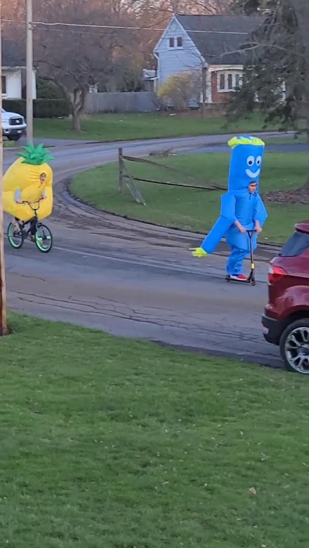 Kids in Inflatable Costumes Ride Their Bikes in Street to Cheer People