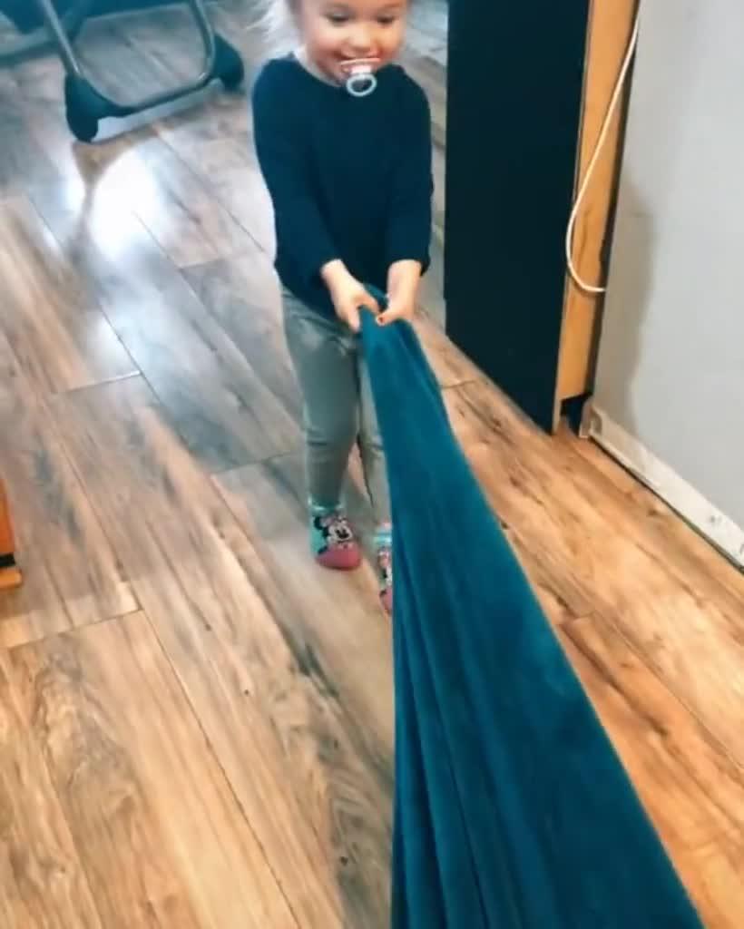 Toddler Drags Around Blanket on Floor With Baby Sister Resting on It