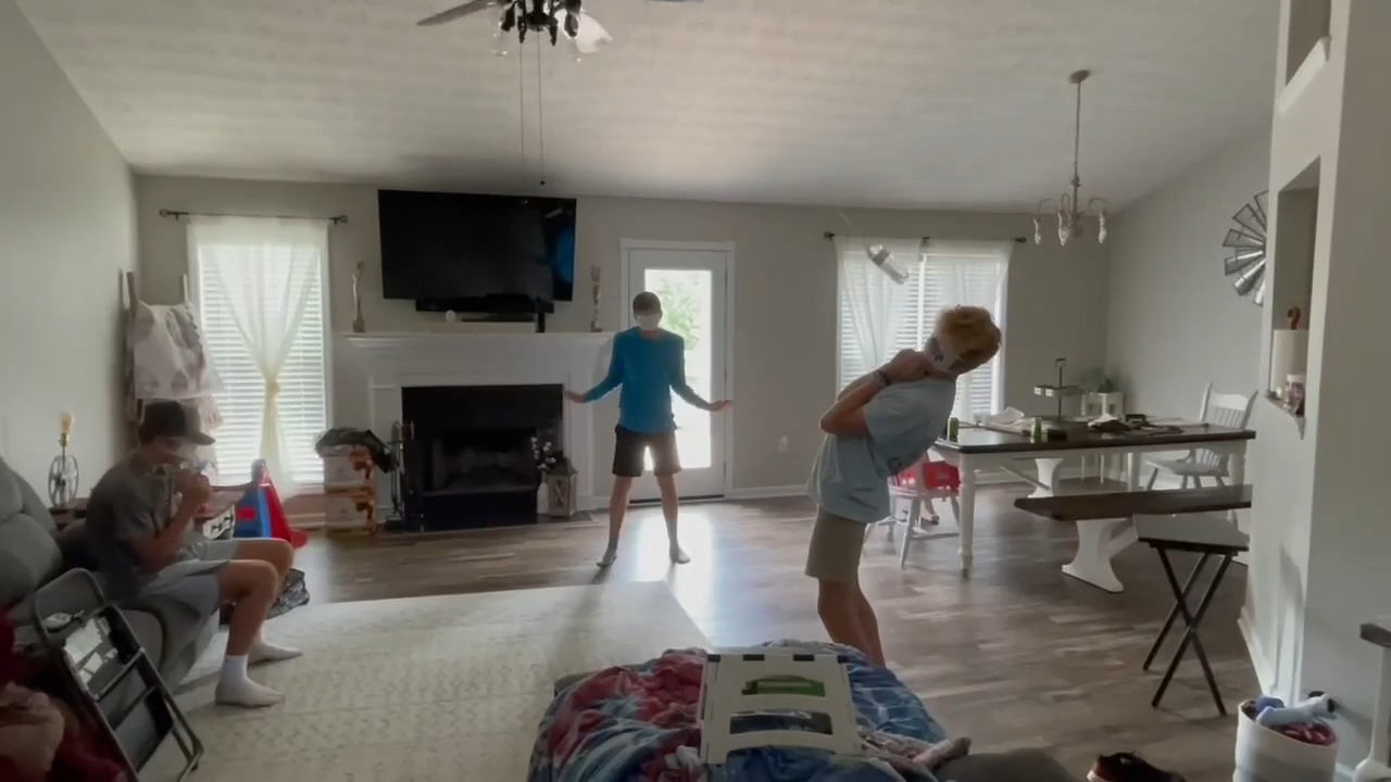Blindfolded Guys Playfully Avoid Water Bottle Attached to Ceiling Fan
