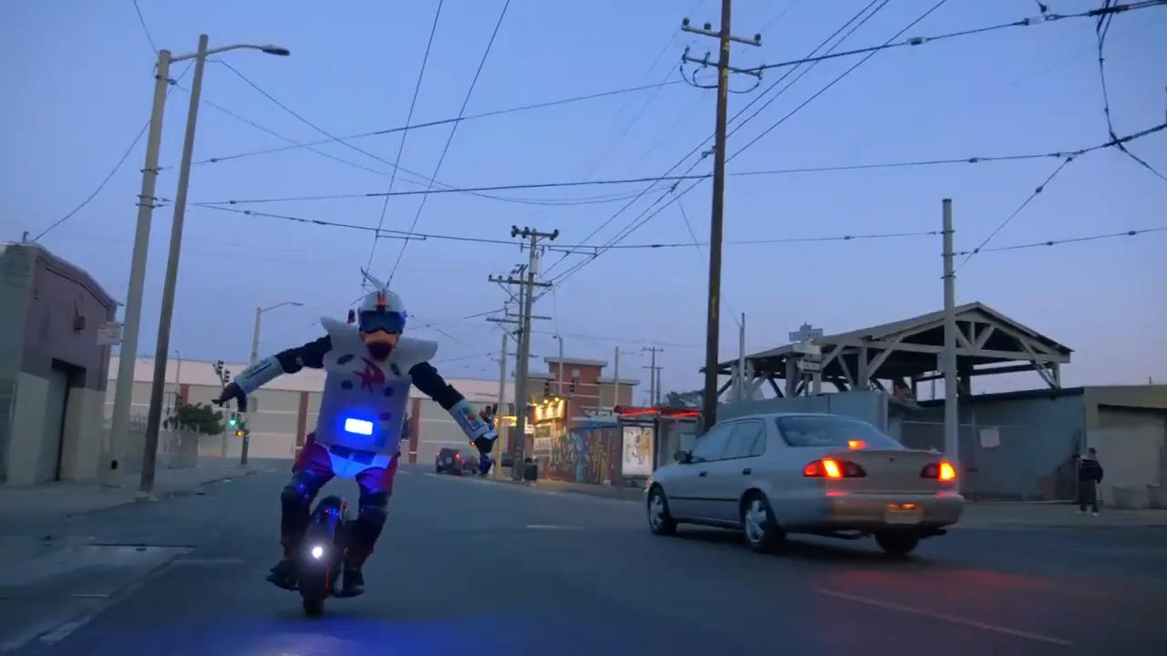Person Wearing Robot Suit And Duck Helmet Costume Rides Electric