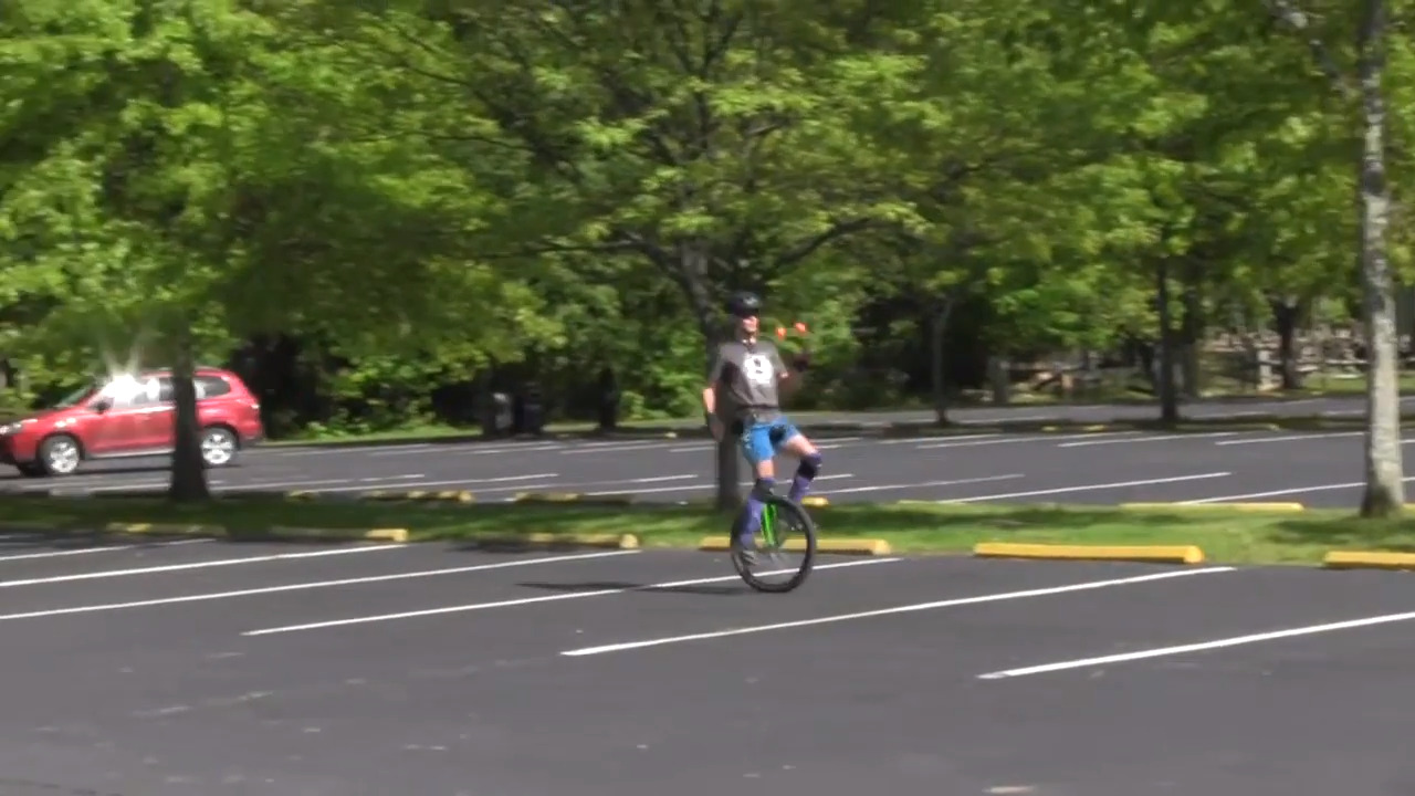 Guy Rides Unicycle Backwards While Juggling Balls Simultaneously