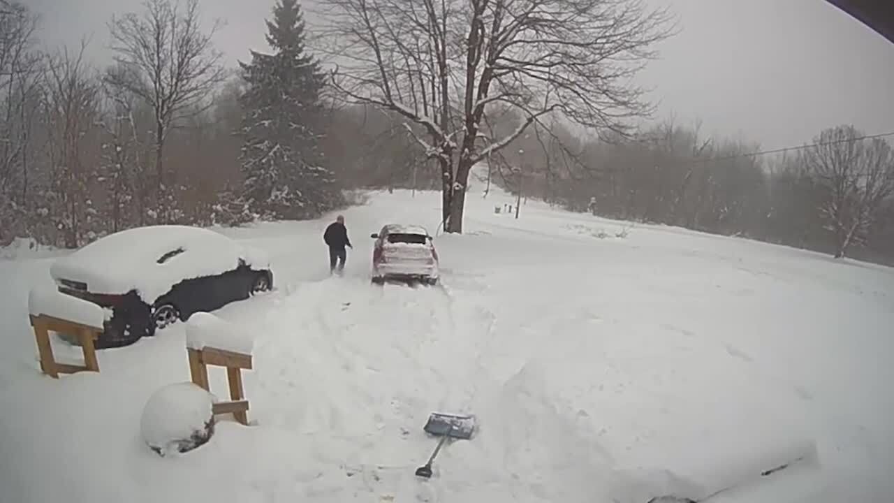 Car Slides Down Snowy Driveway While Man Attempts to Shovel Snow in